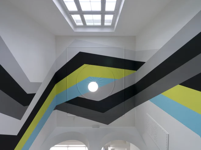 Wandgemälde mit Streifen, das ein ganzes Treppenhaus einer Altbau-Architektur durchzieht