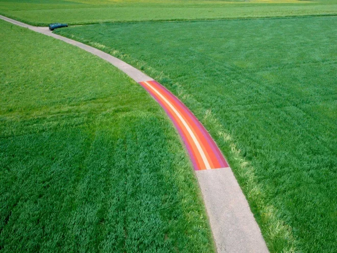 Straßenmalerei in der Schweiz auf einer Landstraße, die durch grüne Felder führt